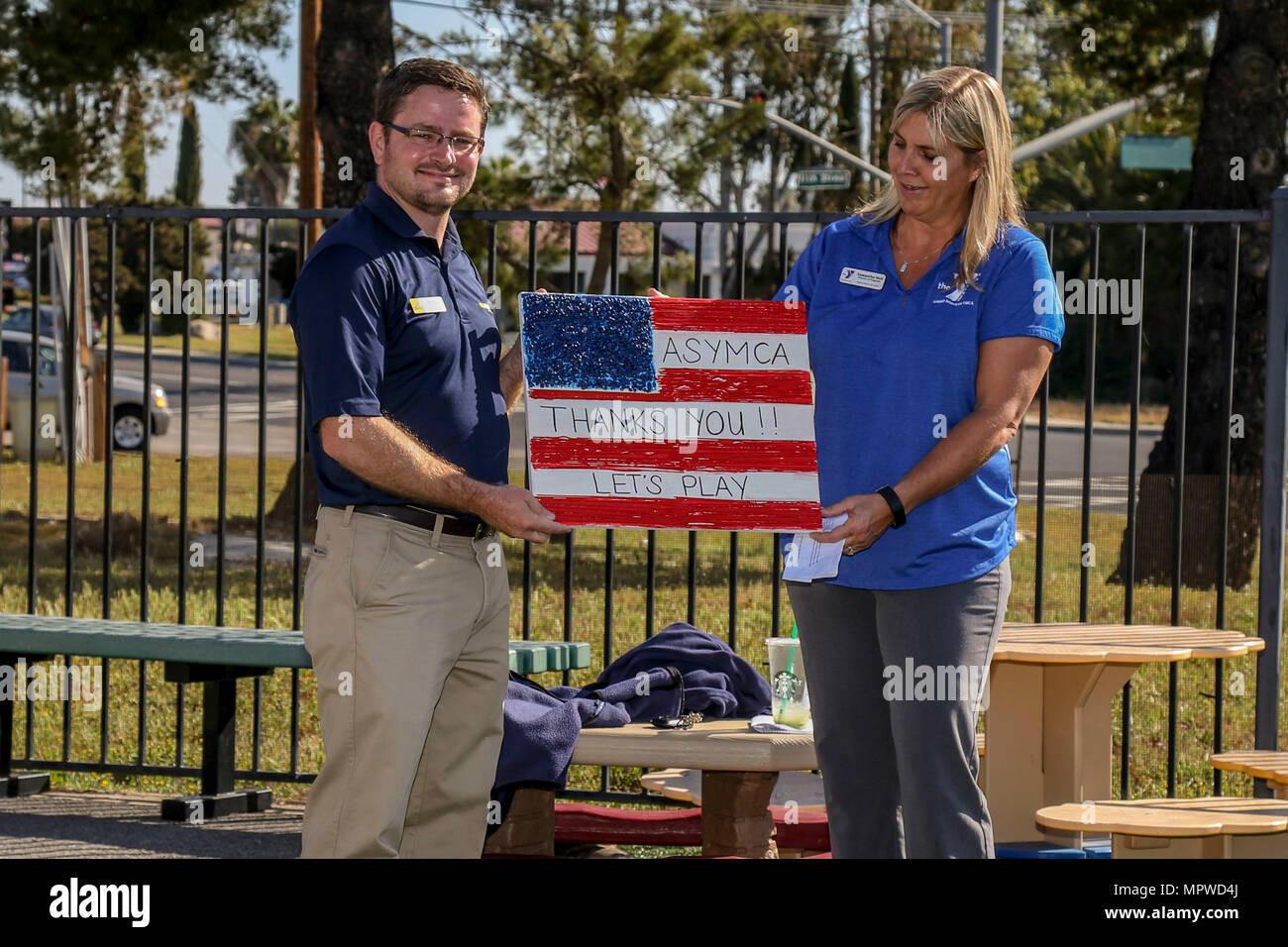 Samantha Holt, Recht, Programme Director für das Armed Services Young Men Christian Association (ASYMCA) Camp Pendleton, präsentiert ein Geschenk als ein Zeichen der Wertschätzung, Rob Reape, senior Einkäufer für Carmax Escondido, während eine "Woche der Play" Veranstaltung am Camp Pendleton, Kalifornien, 20. April 2017. ASYMCA, Fisher Kinderzentrum, erhielt ein Kaboom spielen Stipendium der CarMax Stiftung für militärische Kind Monat, wo ein Phantasie-Spielplatz offenbart wurde. (Foto: U.S. Marine Corps CPL. Brandon Martinez) Stockfoto