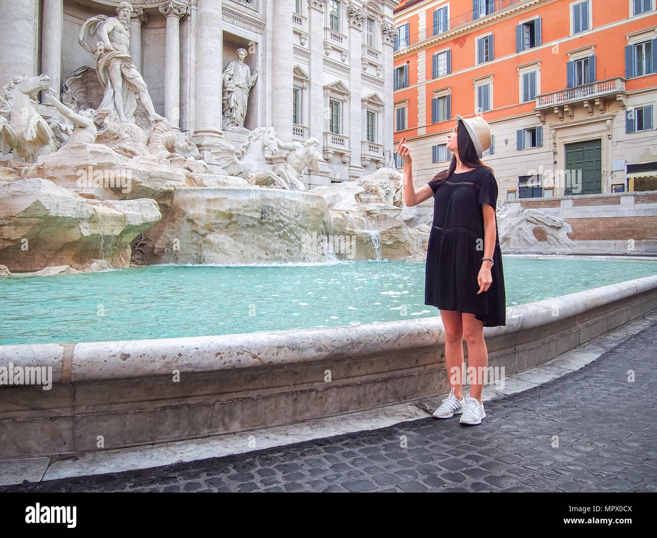 Junge Frau wirft eine Münze in den Trevi-Brunnen in Rom, Italien Stockfoto