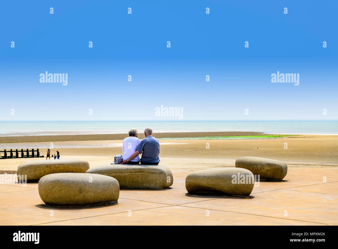 Älteres Paar auf einige große Steine, von denen aus man Meer sitzen Stockfoto