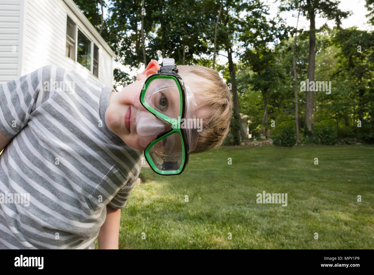 Portrait von verspielten Jungen tragen Schwimmbrille auf der Wiese im Hinterhof Stockfoto