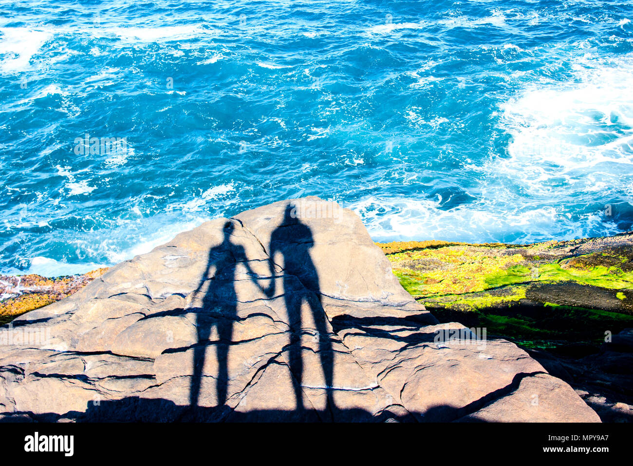 Schatten von Mann und Frau, Hände auf Felsen auf dem Seeweg Stockfoto