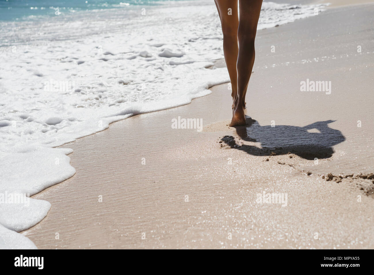 Niedrige Abschnitt der Frau zu Fuß auf Ufer am Strand im Sommer Stockfoto
