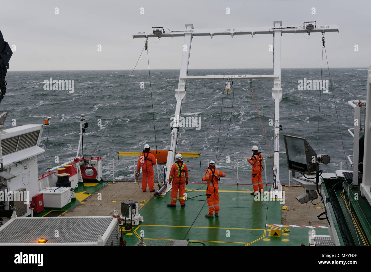 Personal auf dem Achterdeck des Schiffes eine Umfrage Wiederherstellen einer eiva Scanfish mit Magnetometern, von einem rauhen Meer während eine geophysikalische Untersuchung. Stockfoto