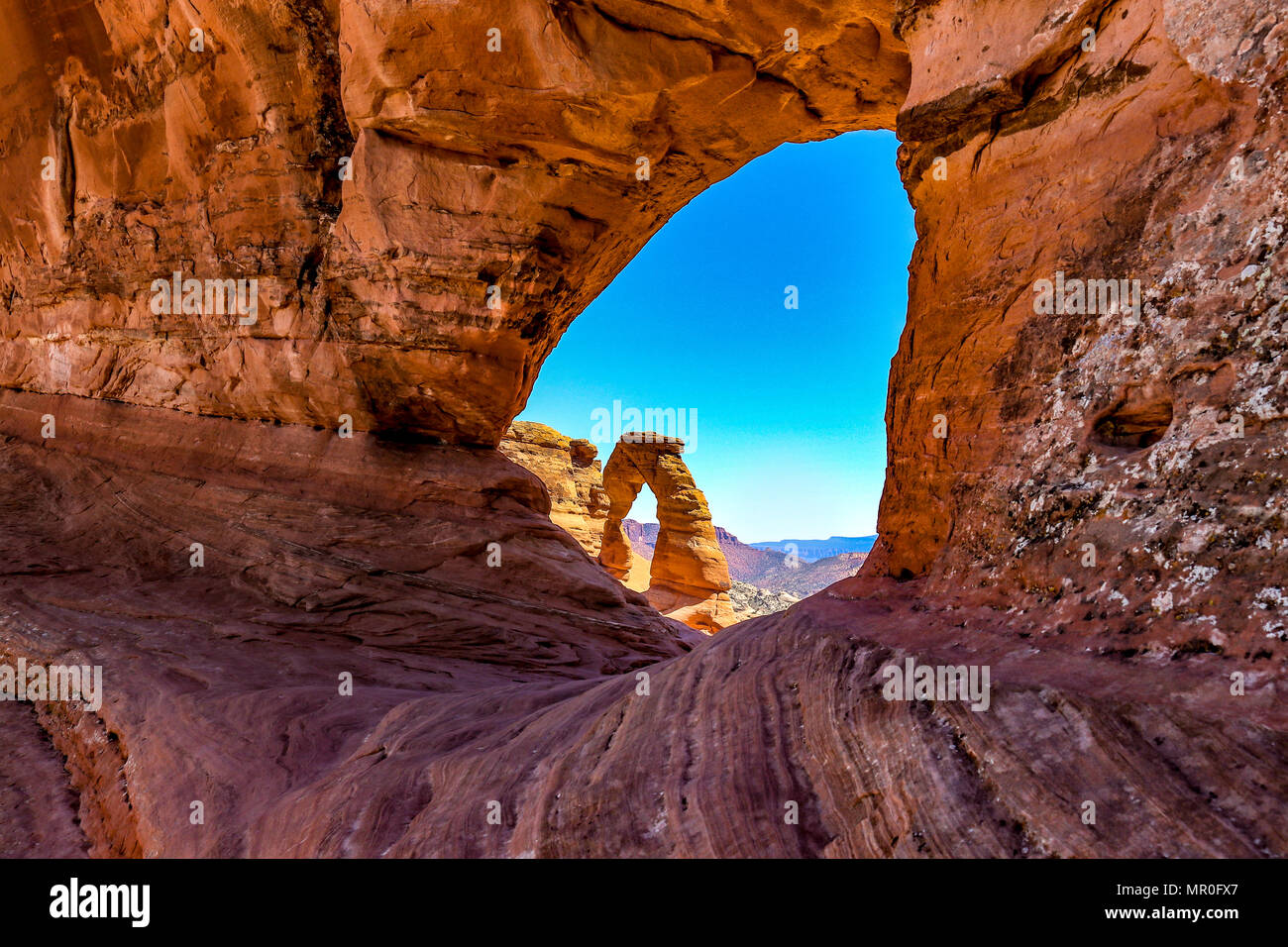 Der Arches National Park, Moab, Utah. Eine Ansicht aus einem der kleineren Bögen zeigt die Zarten Arch im Hintergrund. Ähnelt einer Katze Auge Stockfoto