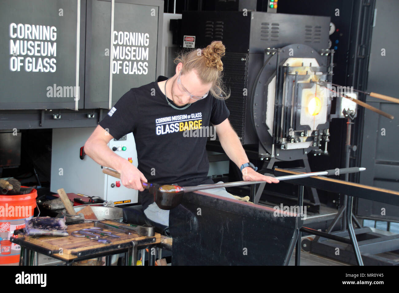 24. Mai 2018, US, New York: Ein Mann ist bei der Arbeit an der "GlassBarge", ein Wasser - glasbläserei Workshop mit direktem Blick auf die Skyline von Manhattan gebunden. Bis zum 28. Mai 2018, das Schiff wird vor der Brooklyn Bridge Park bleiben. Nach seiner New York Aufenthalt, das Schiff wird seinen Weg nach oben Hudson River zum Erie Canal. Foto: Christina Horsten/dpa Stockfoto