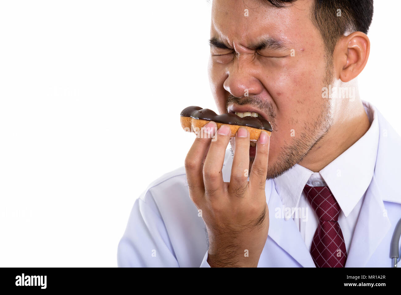 Nahaufnahme von jungen asiatischen Mann Arzt donut Essen mit geschlossenen Augen Stockfoto