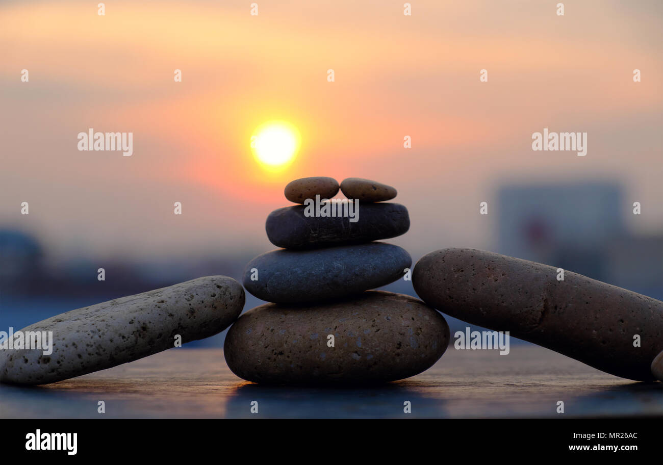 Anordnung Kunst aus Boulder machen erstaunliche Form als Mann auf sunrise Himmel, gelbe Sonne und Pebble Stone in Silhouette, Stapel von Felsen Bilanz Abstract Stockfoto