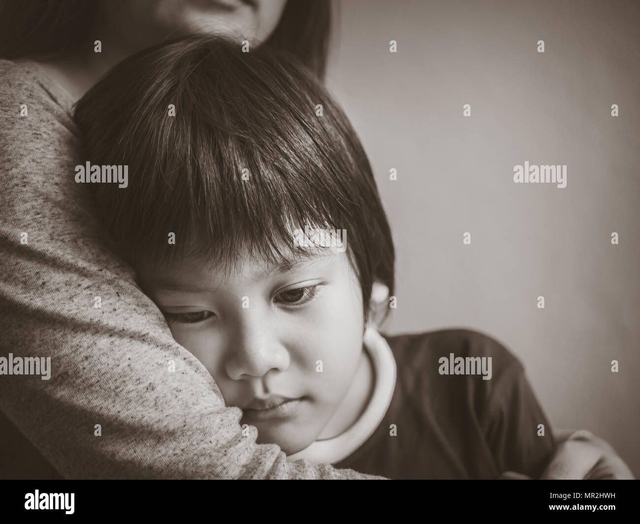 Schwarze und weiße traurige junge Umarmten, von seiner Mutter zu Hause. Die Elternschaft, Liebe und Zusammengehörigkeit Konzept. Stockfoto