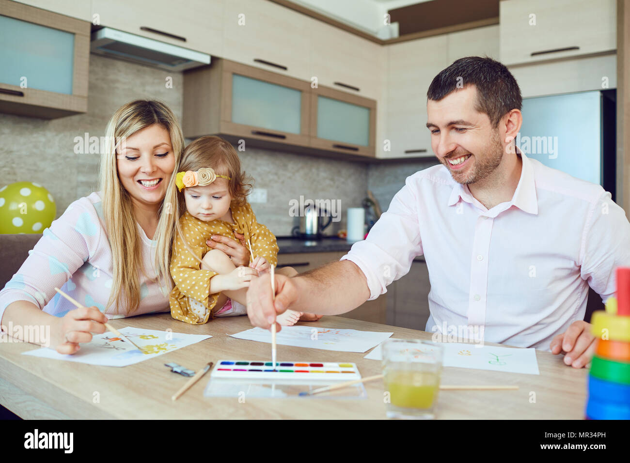 Mutter, Vater und Kind zeichnen zusammen am Tisch. Stockfoto