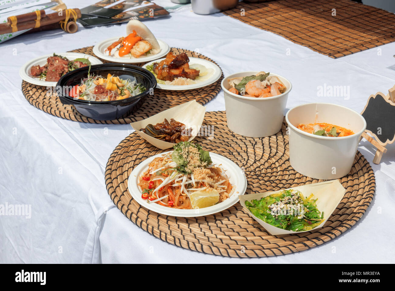 Essen Proben, Variationen von verschiedenen asiatischen Gerichten serviert auf Fächer während der asiatischen Straße Farmers Market. Soft Shell Crab Bao, geröstet Silkworm, Tom Yu Stockfoto