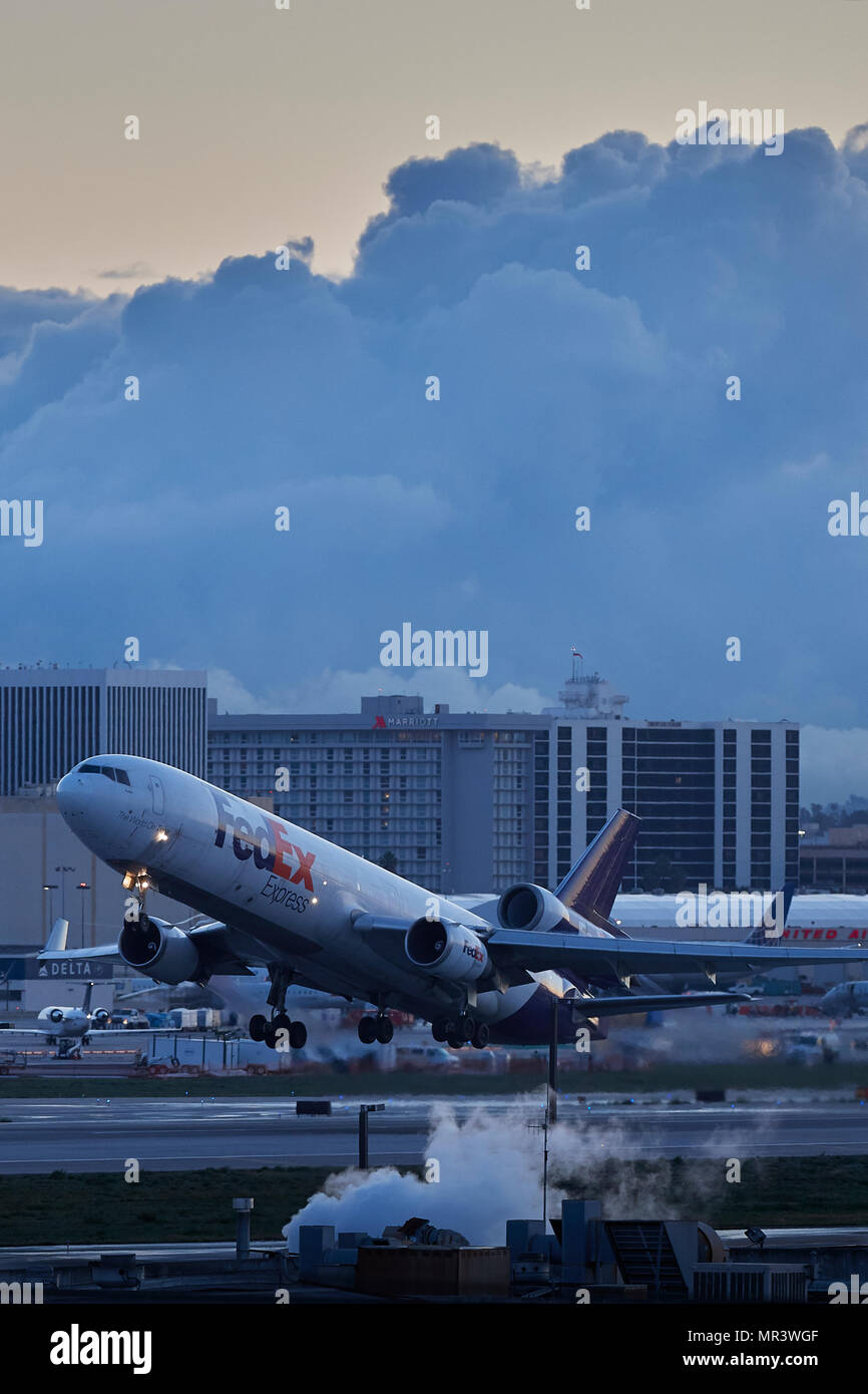 FedEx MD11 Cargo Jet vom Internationalen Flughafen Los Angeles, LAX, bei Sonnenaufgang, eine Versammlung Storm Cloud im Hintergrund. Kalifornien, USA. Stockfoto