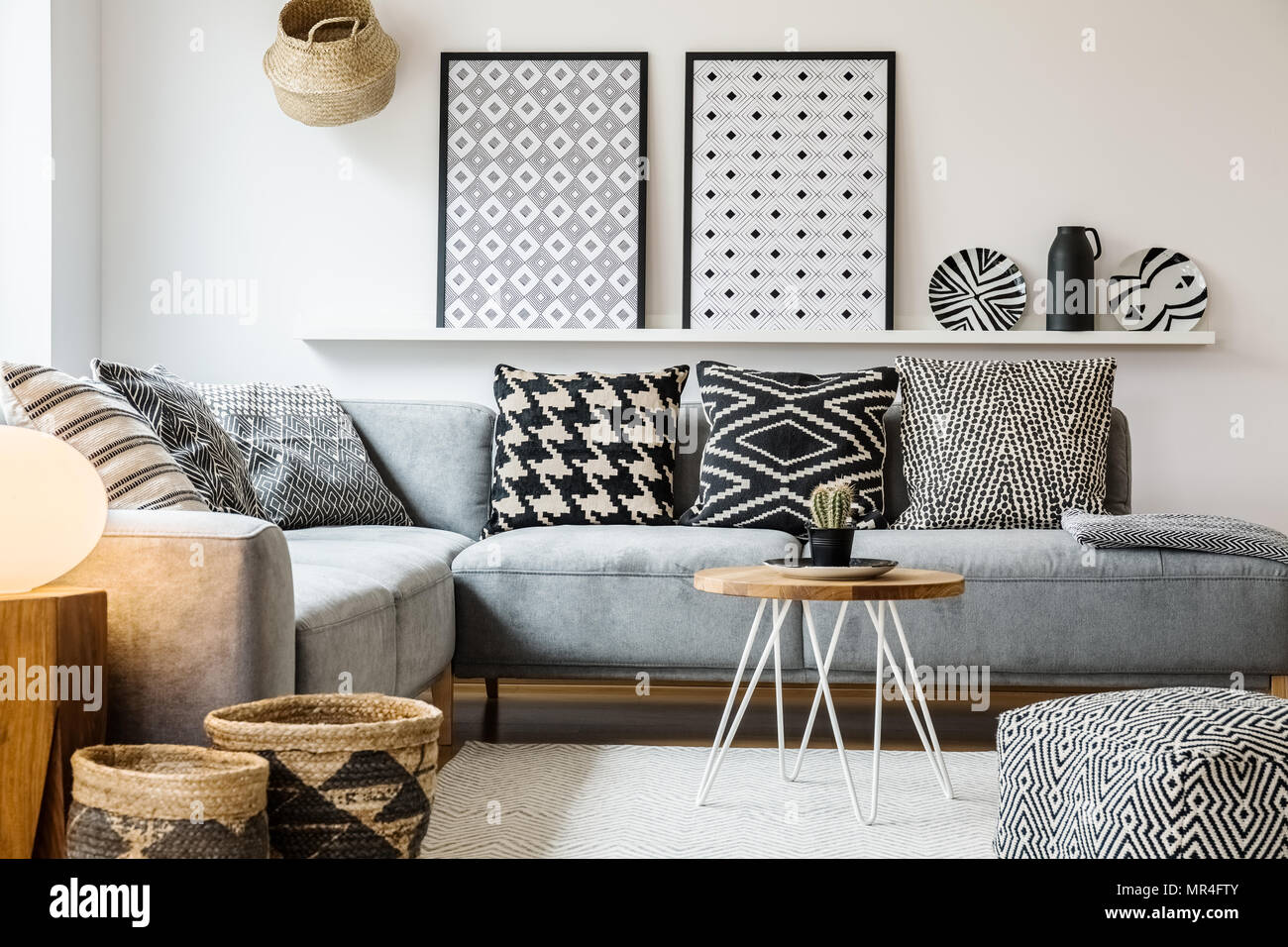 Gemusterten Kissen auf Graue Ecke Sofa in der Wohnung Interieur mit  Plakaten und Puff. Real Photo Stockfotografie - Alamy