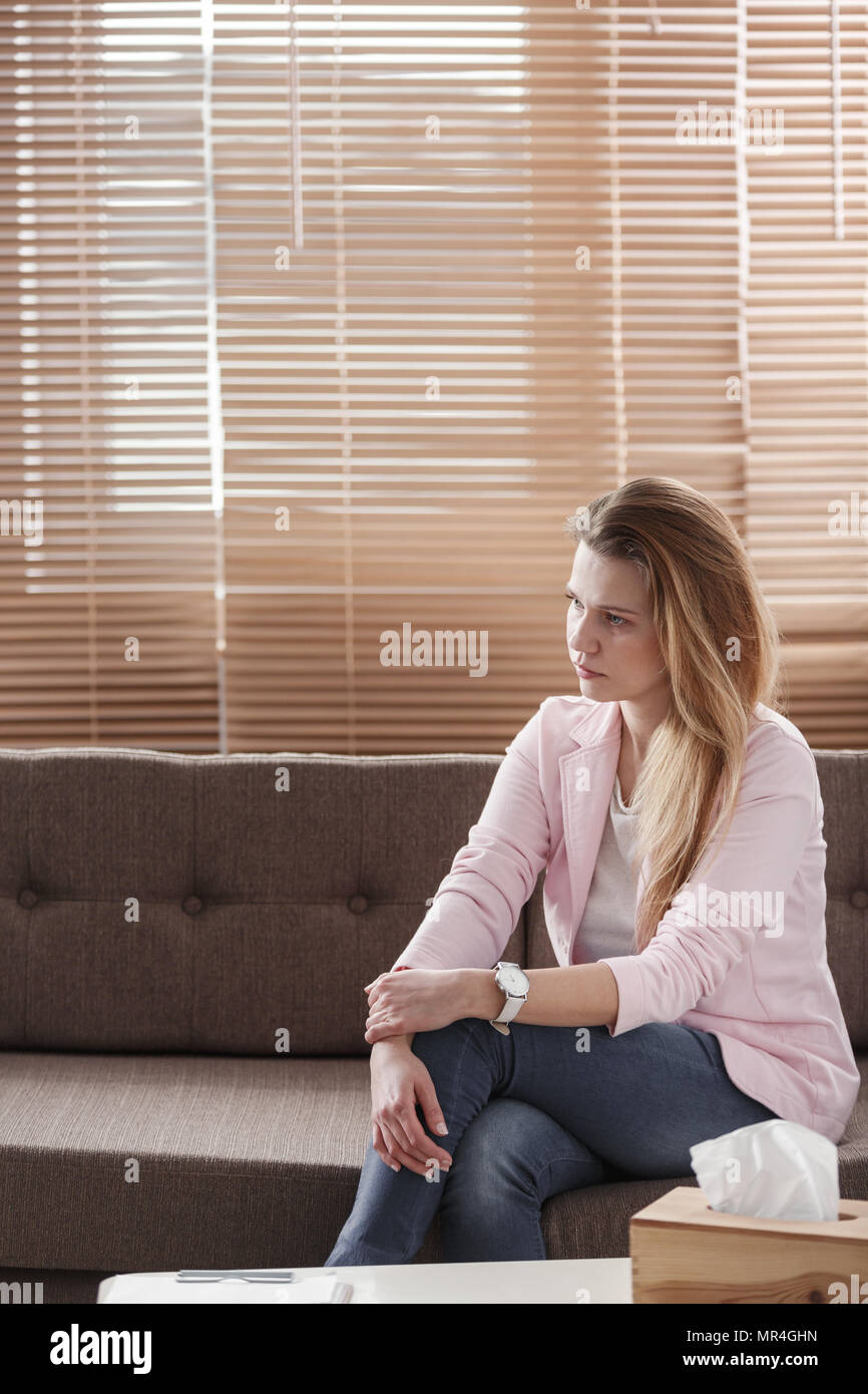 Junge Frau mit Depressionen allein sitzen auf einer Couch mit einem Gewebe, vor ihr während einer Therapiesitzung Stockfoto