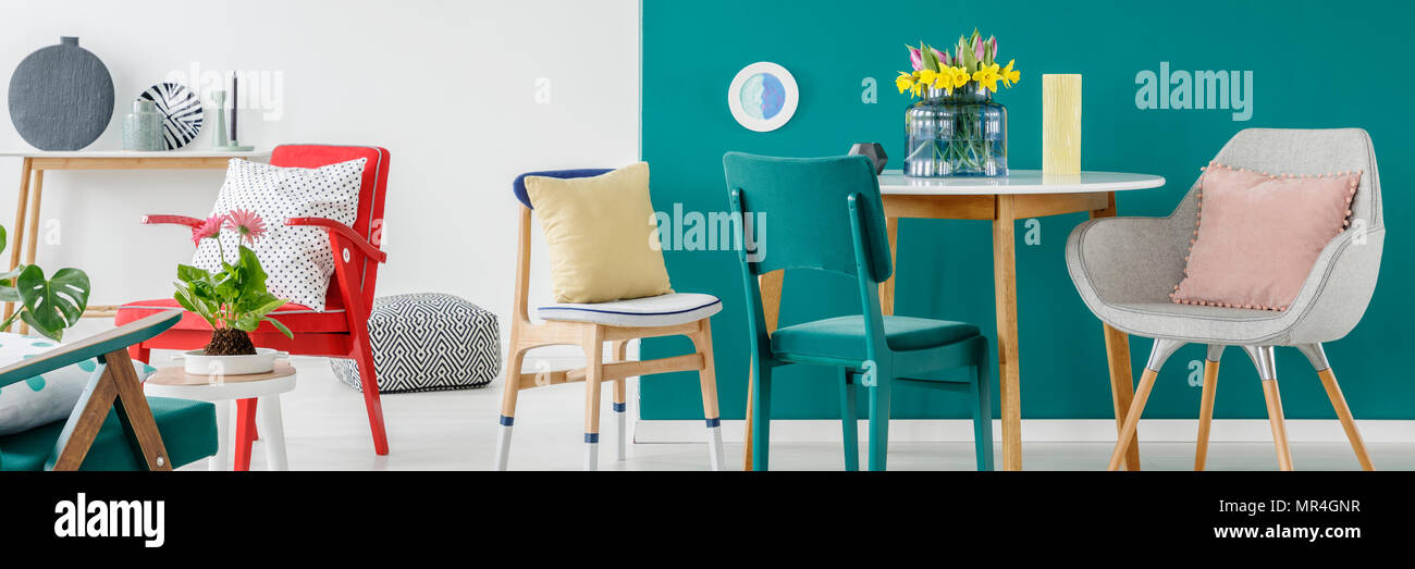 Bunte Stühle mit Kissen in weißen und grünen Wohnzimmer Innenraum mit frischen Blumen auf dem Tisch Stockfoto
