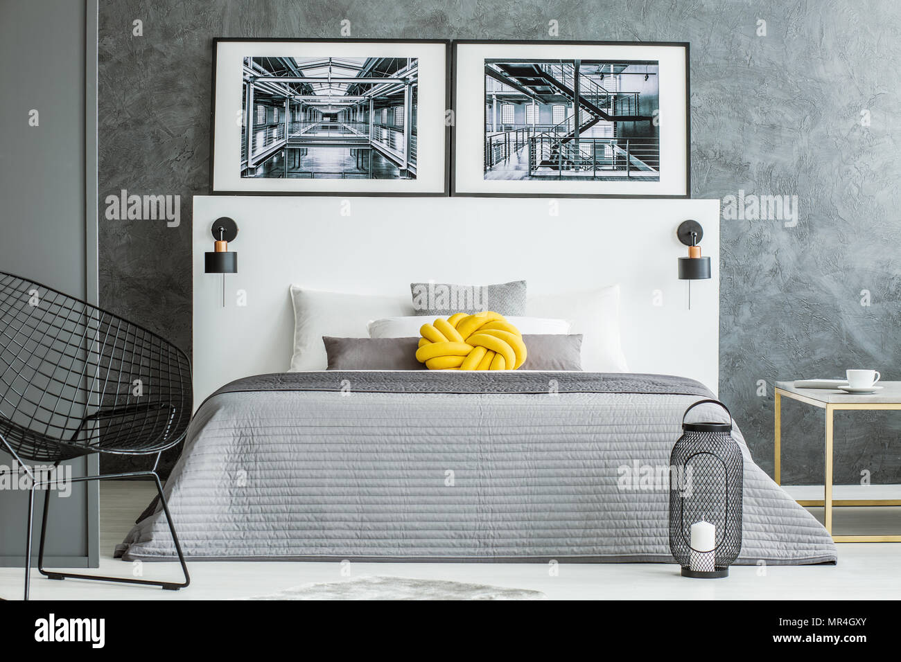 Gelbe Kissen auf grau Bett im Schlafzimmer Innenraum mit Sessel und Plakate  gegen Betonmauer Stockfotografie - Alamy