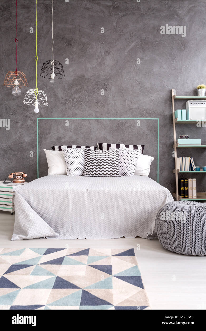 Grau Schlafzimmer mit Teppich, stilvolle Pendelleuchte und dekorative Wand Putz Stockfoto