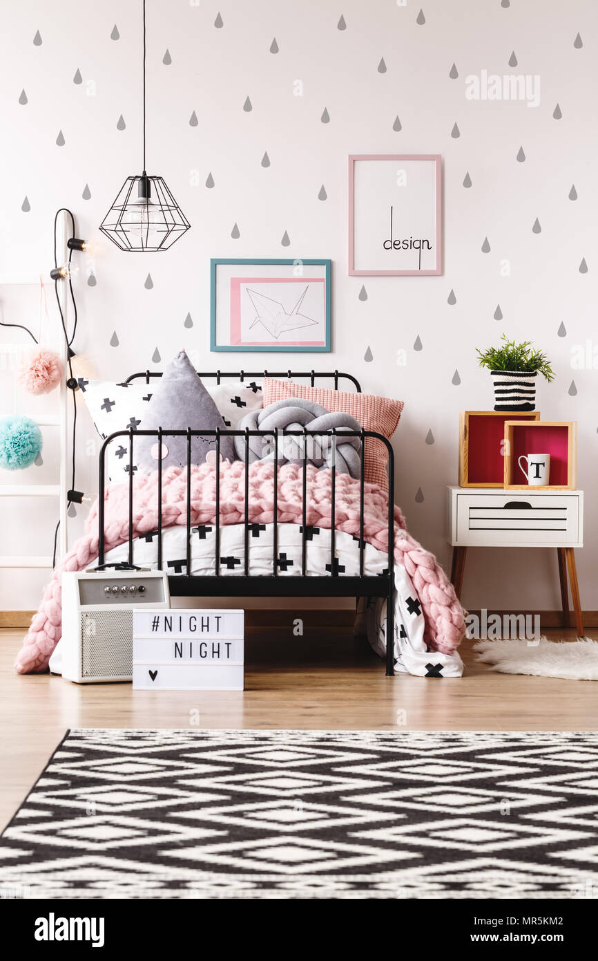 Werk in gestreiften Topf auf Nachttisch neben dem Bett mit Stricken rosa Decke in Pastelltönen Kinder Zimmer Stockfoto