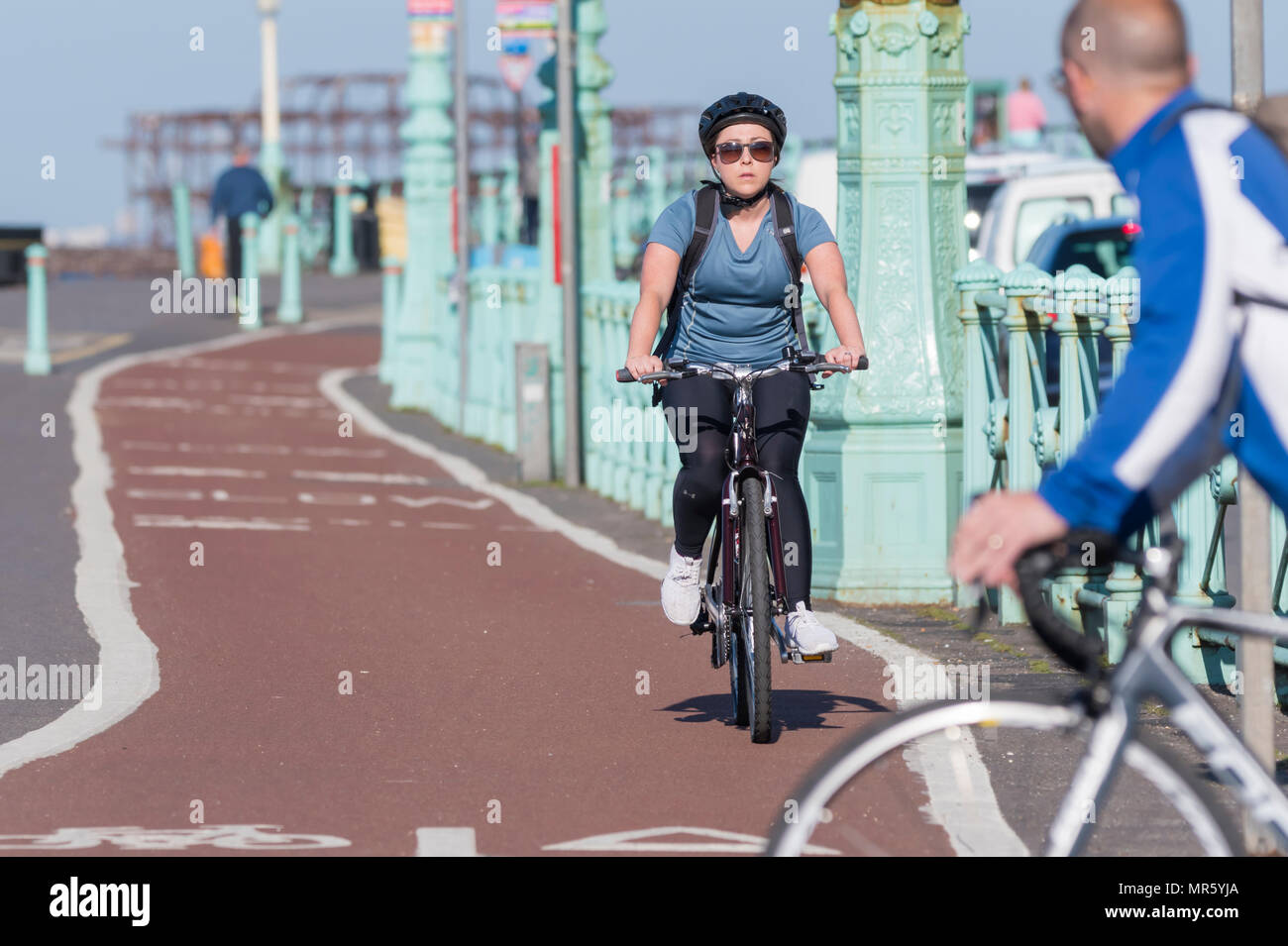 Eine Frau Radfahren auf einem Radweg auf einem Fahrrad Lane mit Helm mit einem anderen Radfahrer ziehen vor ihr in Brighton, East Sussex, UK. Stockfoto