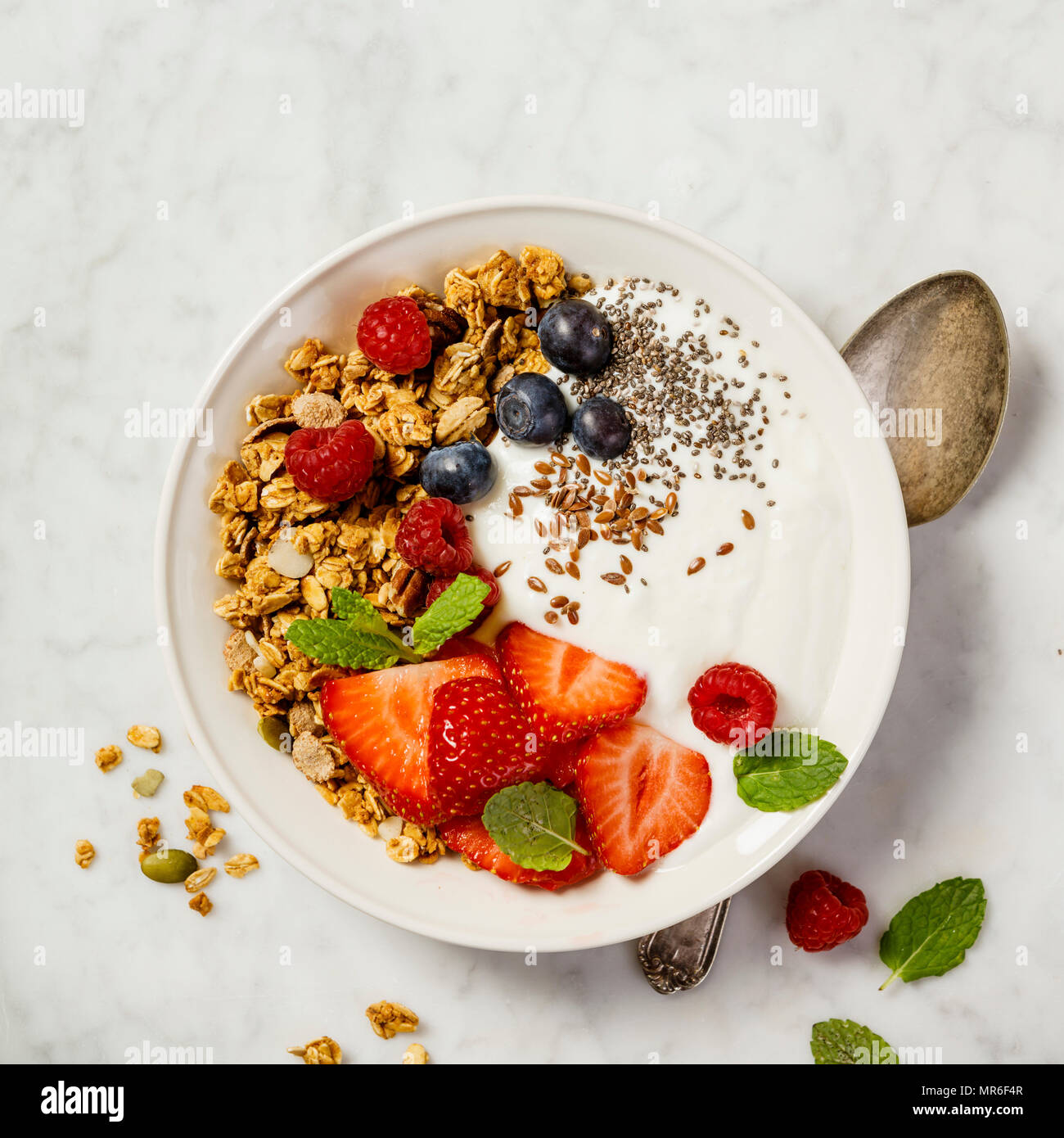 Schüssel mit hausgemachtem Müsli mit Joghurt und frischen Beeren auf weißem Hintergrund. Ansicht von oben, flach. Gesundes Frühstück Konzept. Platz für Text Stockfoto