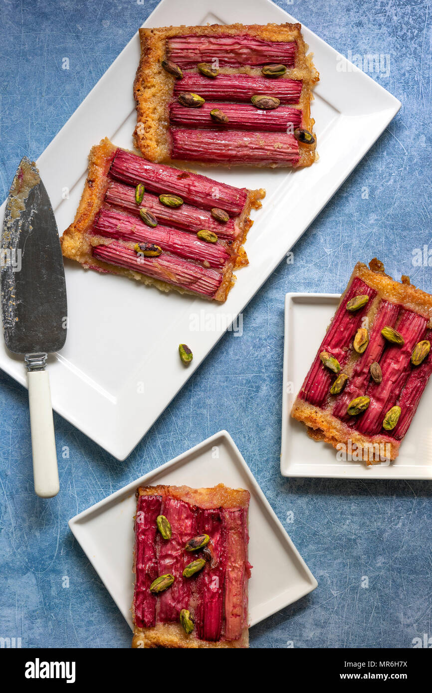 Stücke von Rhabarber und Pistazien tart auf Platten mit einem Kuchen server. Stockfoto