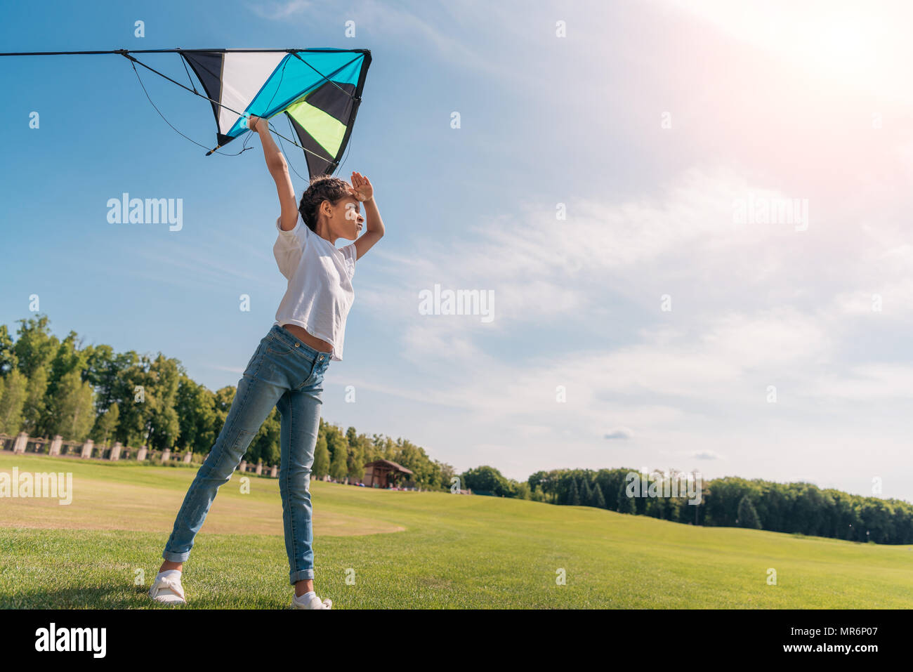 Seitenansicht des kleinen Mädchen, die sich einen Drachen auf der grünen Wiese zu starten Stockfoto