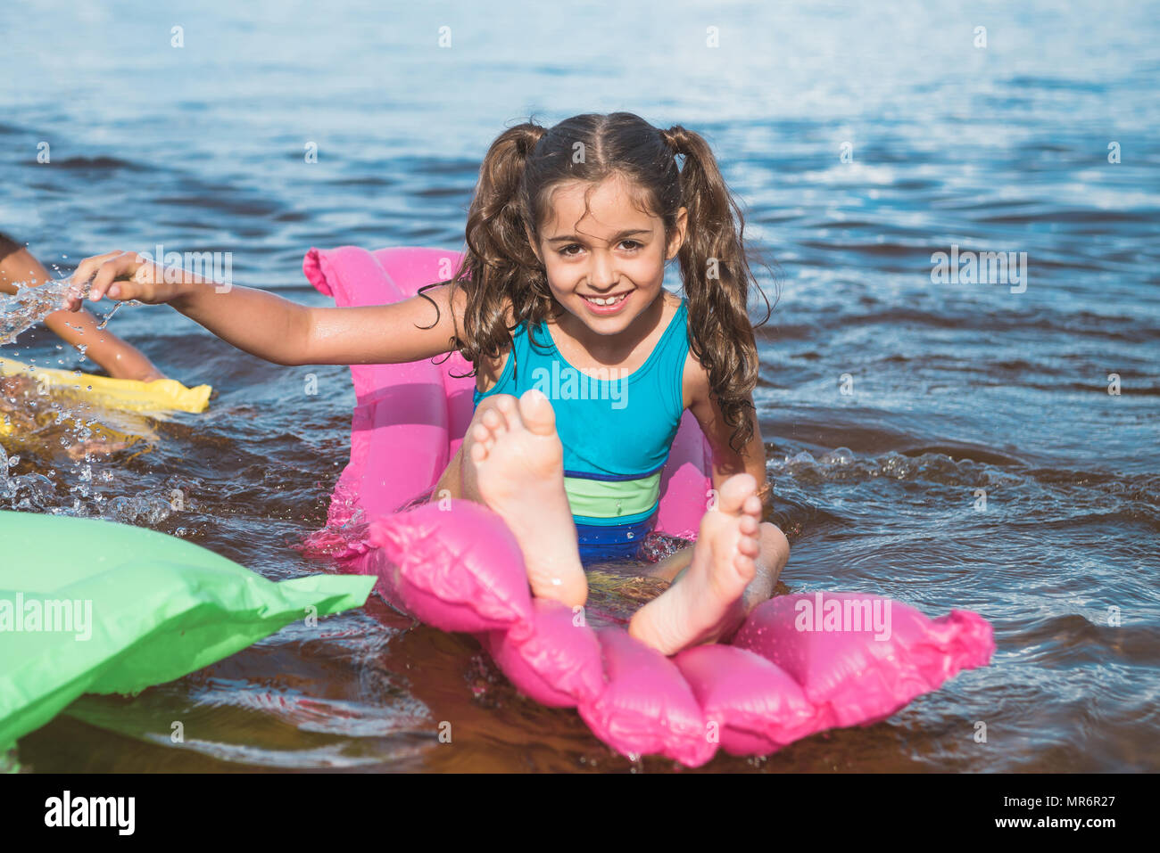 Fröhliches kleines Mädchen schwimmen auf aufblasbaren Matratzen auf See Stockfoto