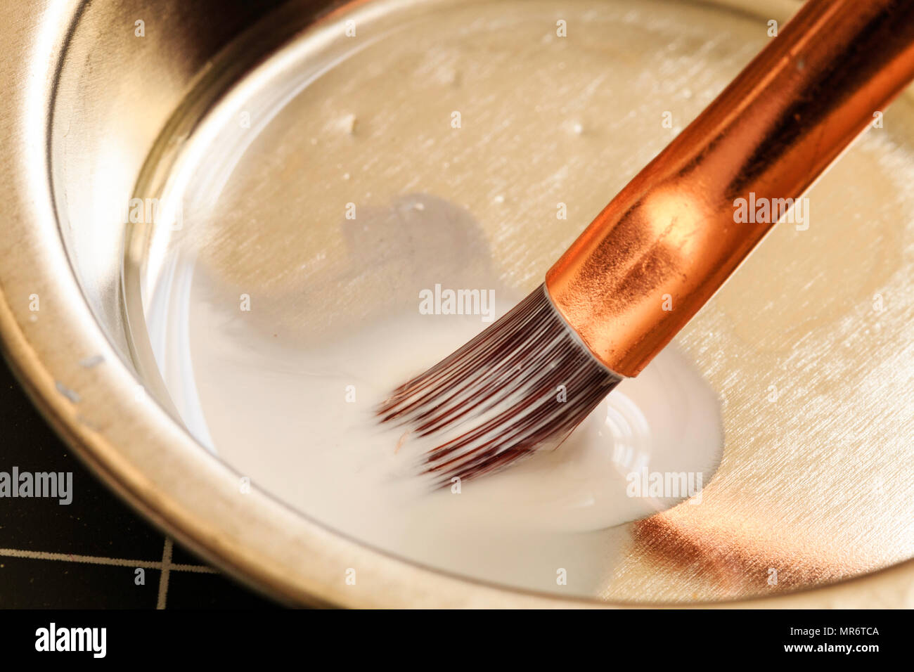 Kleine Modellierung Pinsel in der Schüssel gereinigt nach Gebrauch mit Verdünner. Einige verschwommene Bewegung. Haare der Bürste getränkt in Flüssigkeit. Stockfoto