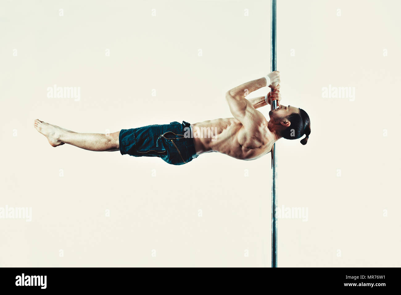 Junge starke Pole Dancing Mann auf Wand Hintergrund. Weich sepia Tönung. Stockfoto