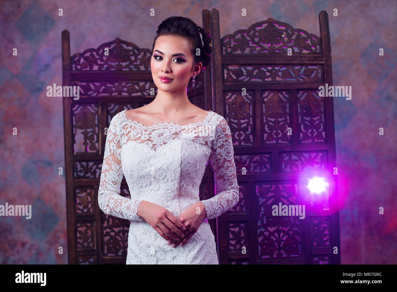 Junge asiatische Frau in weißem Kleid mode Portrait mit hellen rosa Licht auf Hintergrund Stockfoto