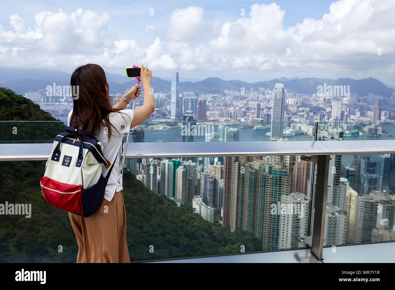 Ein sightseer nimmt Fotos von Hong Kong mit Blick in Richtung Kowloon, wie vom Victoria Peak auf Hong Kong Island gesehen und mit Blick auf die Stadt. Stockfoto