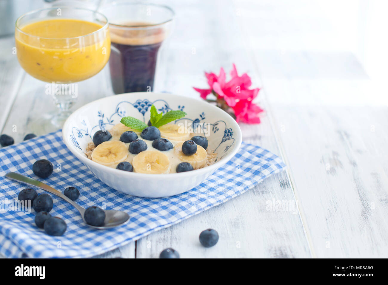 Köstliches Frühstück Komposition. Schüssel mit Bio Müsli mit Banane, Leinsamen, frische Beeren, Kaffee, fover rustikalen Holzmöbeln Kulisse, kopieren. Ansicht von oben. Stockfoto