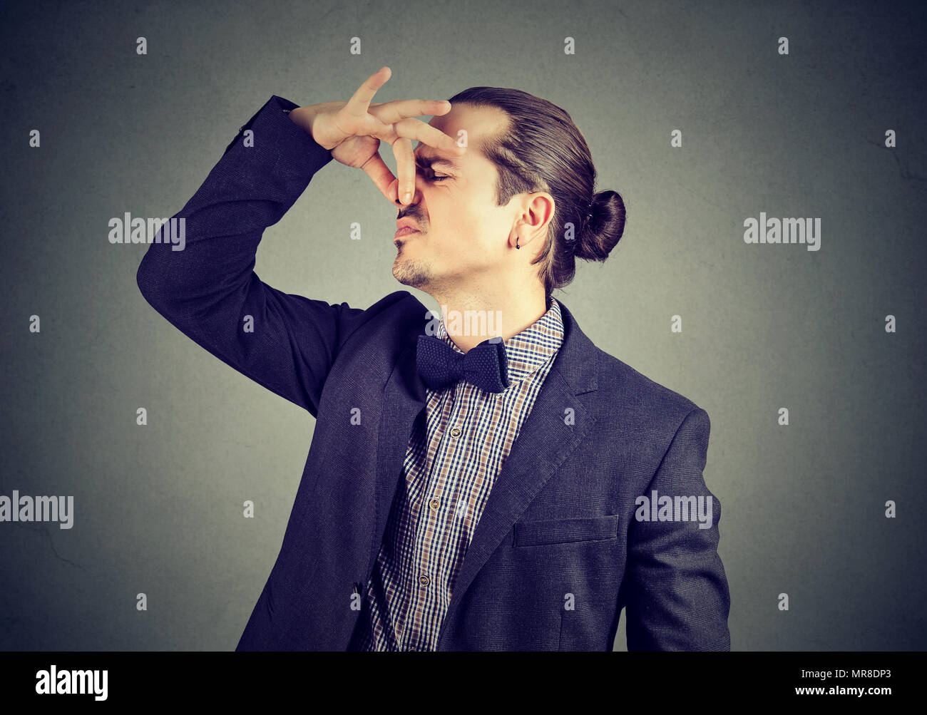 Angewidert Mann kneift Nase mit den Fingern blickt mit Abscheu etwas stinkt schlechter Geruch auf Wand Hintergrund isoliert. Menschliches Gesicht Ausdruck Reaktion Stockfoto