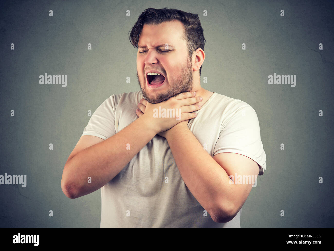 Chunky legerer Mann runzelte die Stirn und erstickt in Allergie und halten sich an den Händen an den Hals mit geschlossenen Augen. Stockfoto