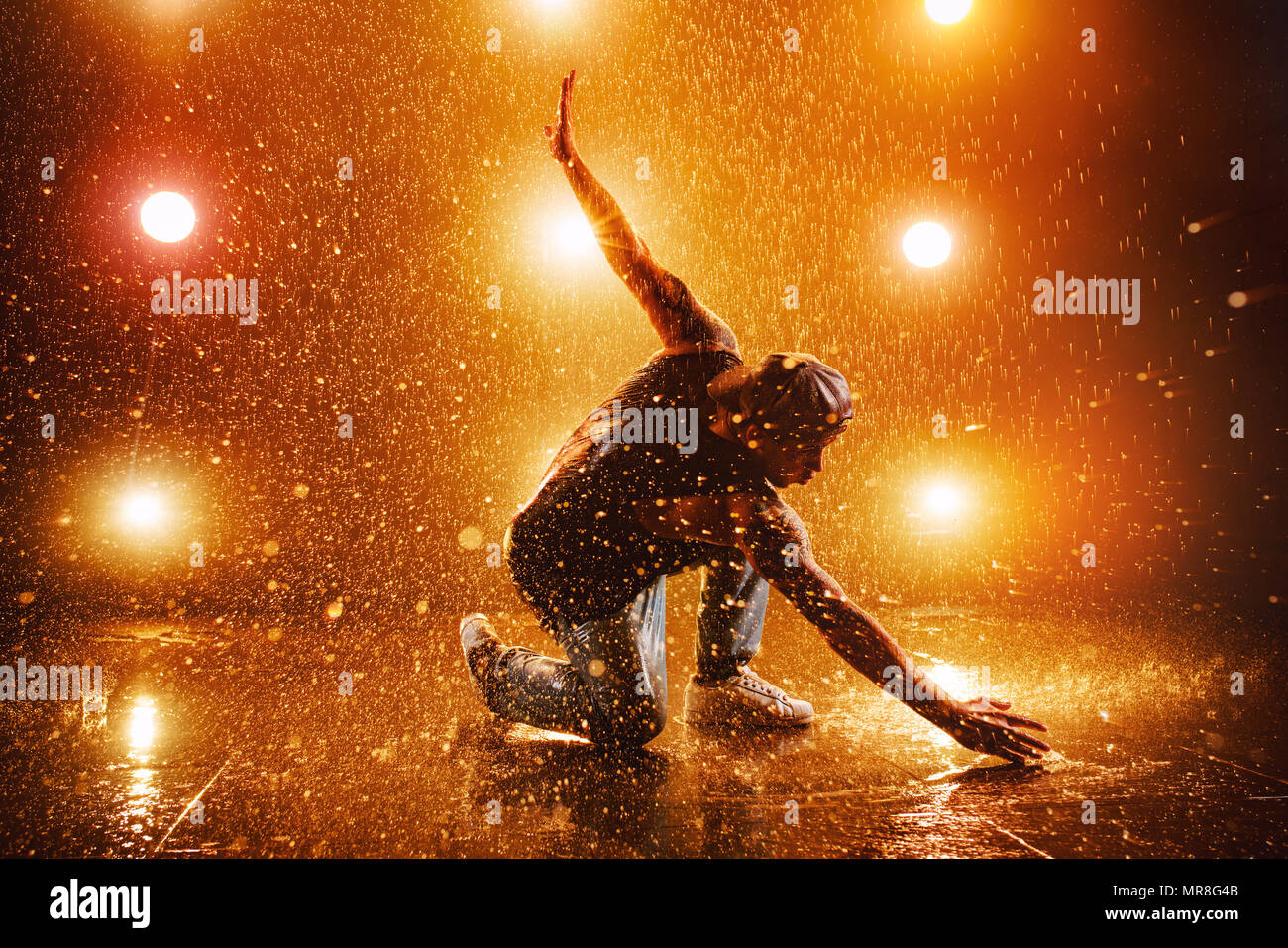 Junger Mann pause Tanzen im Club mit Licht und Wasser. Tattoo am Körper. Stockfoto