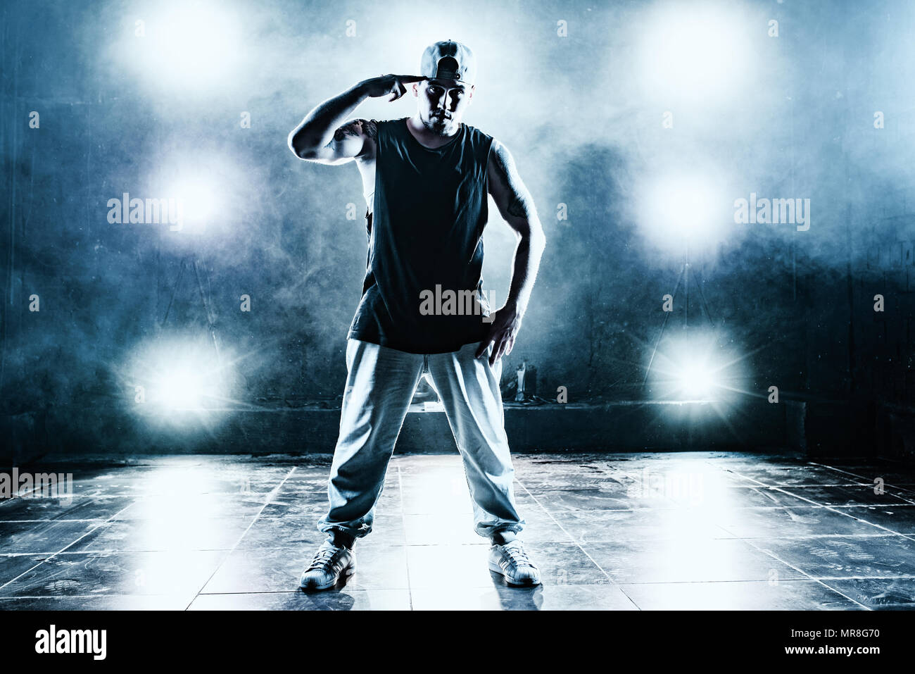 Junger Mann Breakdancer im Club mit Licht und Rauch. Tattoo am Körper. Blau getönten Farben. Stockfoto
