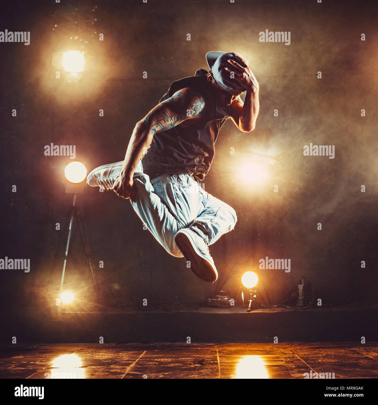 Junge cool Mann Breakdancer im Club mit Licht und Rauch springen. Tattoo am Körper. Stockfoto