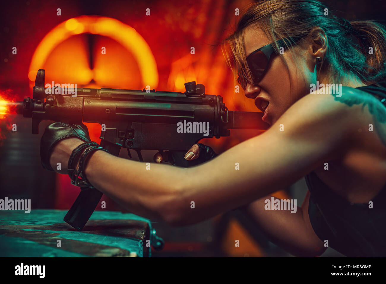 Junge starke Frau Krieger Schießen von Machine Gun in dramatischen urbanen Nacht Szene. Tattoo am Körper. Stockfoto