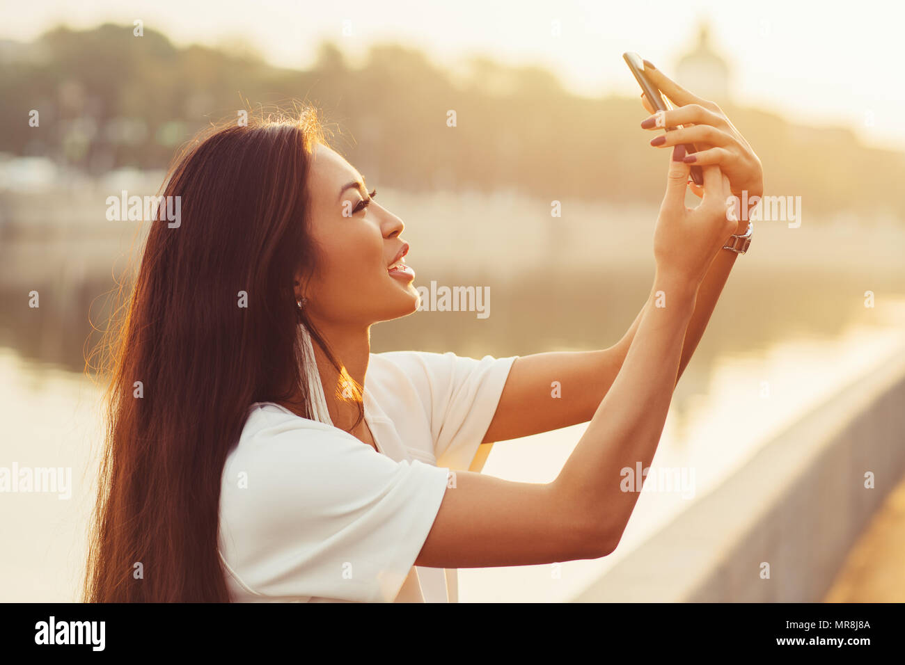 Junge asiatische Frau tun selfie auf city river Hintergrund am sonnigen Morgen Stockfoto