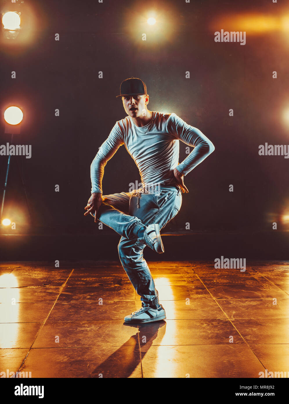 Junger Mann pause Tanzen im Club mit Licht und Rauch. Warme Farben. Stockfoto