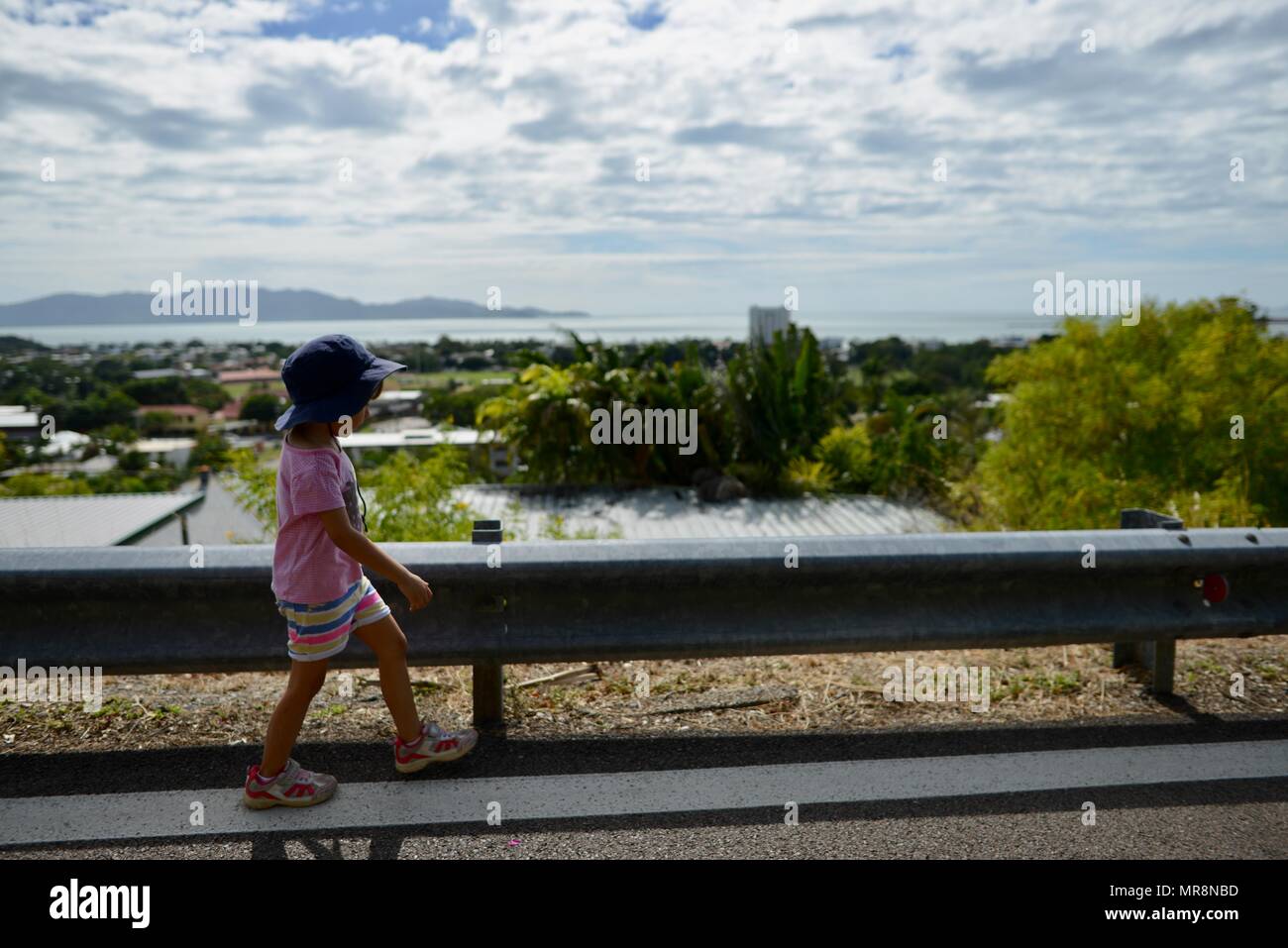 Ein junges Mädchen geht auf eine Straße mit Blick auf Magnetic Island, Castle Hill, QLD 4810, Australien Stockfoto