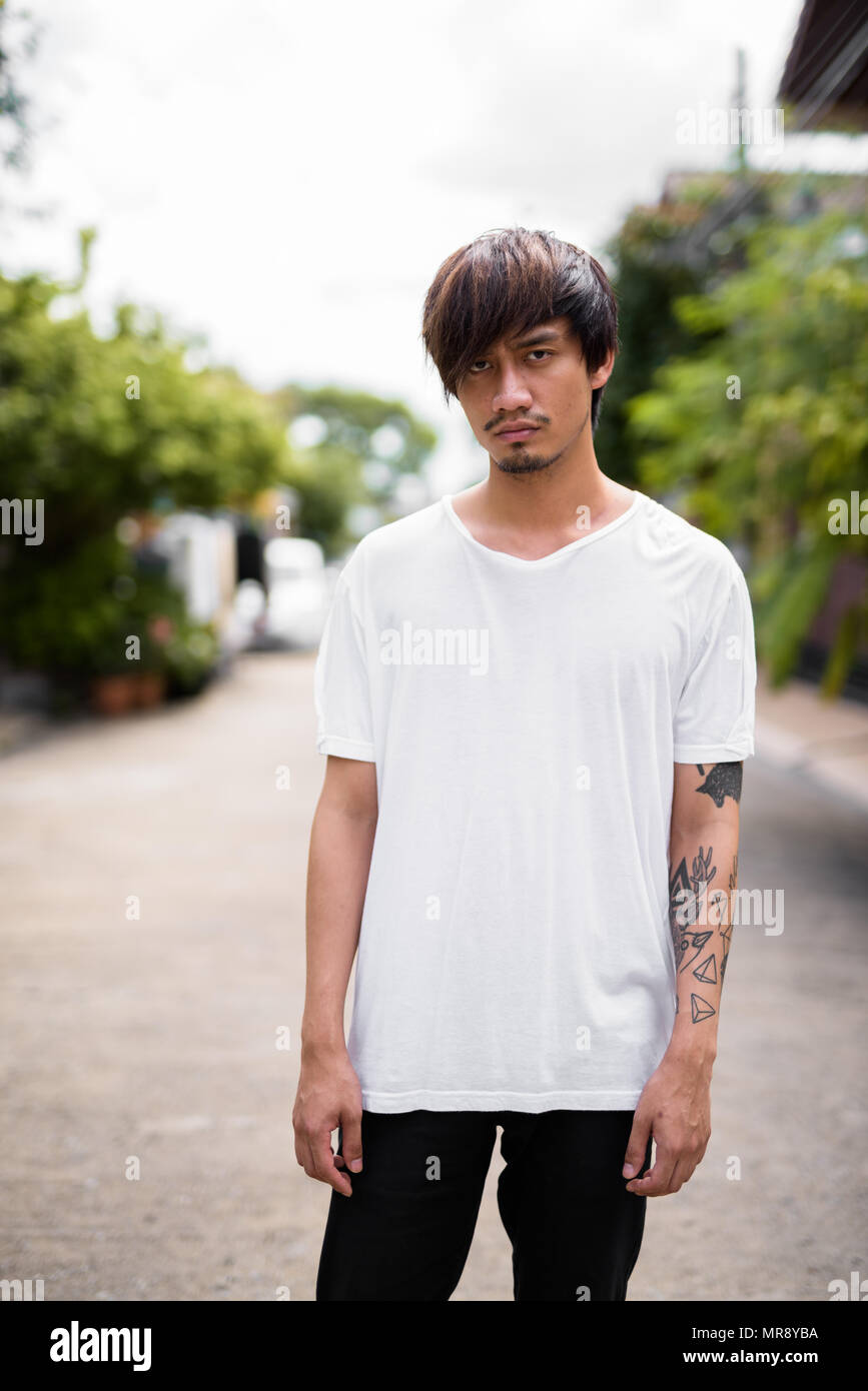 Jungen asiatischen Menschen mit Tätowierungen in den Straßen im Außenbereich Stockfoto
