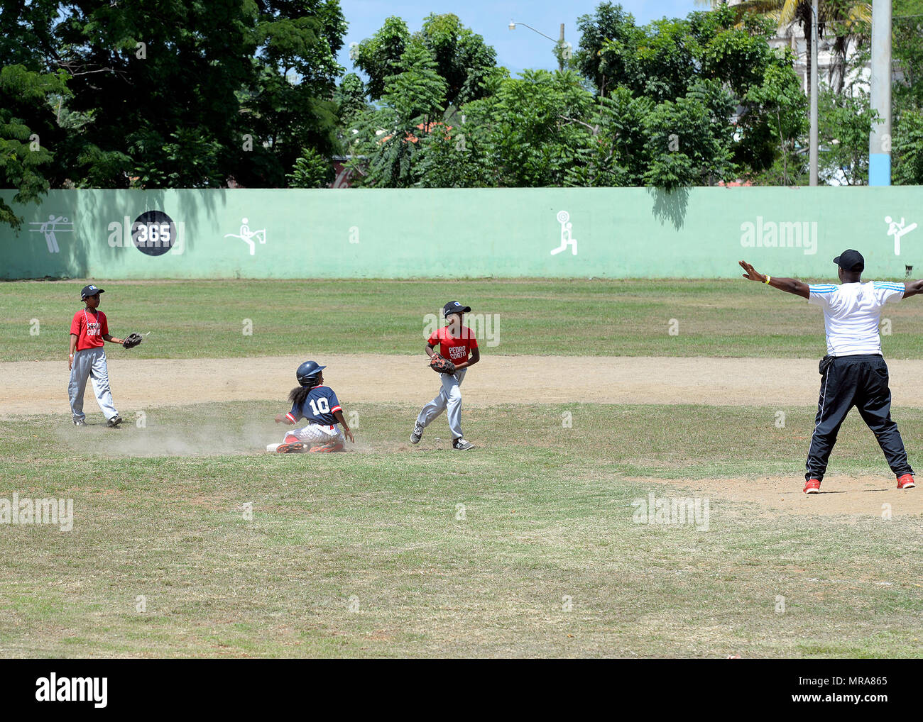 Ein Spieler rutschen sicher in die zweite Basis am Nachmittag Spiel eines Baseball Clinic die Task Force für Bereich Kinder Mai 20, 2017, in San Juan de la Maguana, Dominikanische Republik gehostet wird, als Teil der neuen Horizonte 2017. Der baseball Clinic, die von der Task Force in Zusammenarbeit mit verschiedenen Nichtregierungsorganisationen und anderen Organisationen organisiert, bot US-Mitglieder die Möglichkeit, ehemalige Major League Baseball Spieler und Trainer auf ein denkwürdiges Ereignis für 450 Kinder, Eltern und andere Teilnehmer zu unterstützen. (U.S. Air Force Foto von Master Sgt. Karen J. Tomasik) Stockfoto