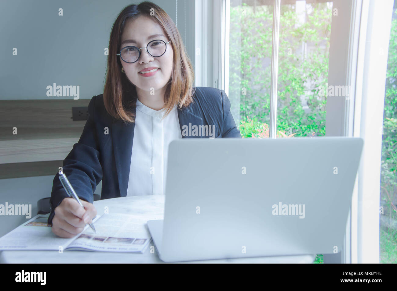 Junge Geschäftsfrau im asiatischen Stil lächelnd und glücklich das Arbeiten mit einem Notebook und dem Internet zu finden und per e-mail Daten, Buchhaltung, analytische Summa senden Stockfoto
