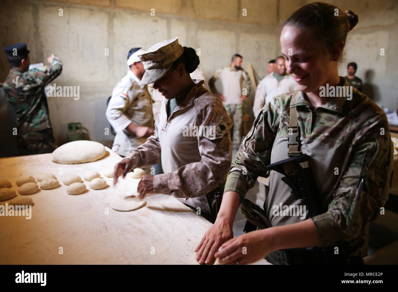 Us Marine Corps Staff Sgt. Shakelia Holz, ein Food Service Spezialist mit Special Purpose Marine Air-Ground Task Force-Crisis Response-Central Befehl und Sgt. Susan Molinar, eine kulinarische noncommissioned Officer mit dem 314 unterstützen Sustainment Bataillon, Rolle Teig khubuz zu machen, eine traditionelle Irakische Fladenbrot im Al Asad Air Base, Irak, 4. Mai 2017. Holz angewiesen, irakische Soldaten mit der 7 irakische Armee Abteilung auf Fähigkeiten und Beschäftigung eines Ozti Feld Küche (Ofk) während einer beraten und Mission zur Unterstützung der Task Force Al Asad unterstützen. Task Force Al Asad Züge irakischen Streitkräfte Stockfoto