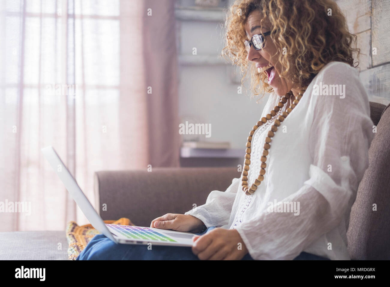 Happyness nach einem Erfolg bei der Arbeit oder ein Treffen mit Freunden auf Linie für schönes Modell zu Hause mit einem Laptop auf den Beinen sitzen. Fenster Licht indoor Home sene. Stockfoto