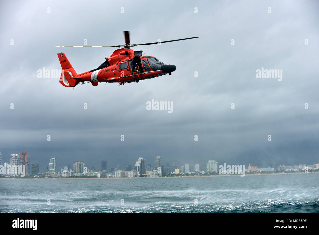 Petty Officer 3rd Class Bryan Evans, ein Coast Guard Air Station Miami Rettungsschwimmerin, bereitet sich für den freien Fall und die Bereitstellung von einem MH-65 Dolphin Helikopter östlich von Miami Beach am 6. Juni 2017. (Küstenwache Foto von Petty Officer 3. Klasse Eric D. Woodall) Stockfoto