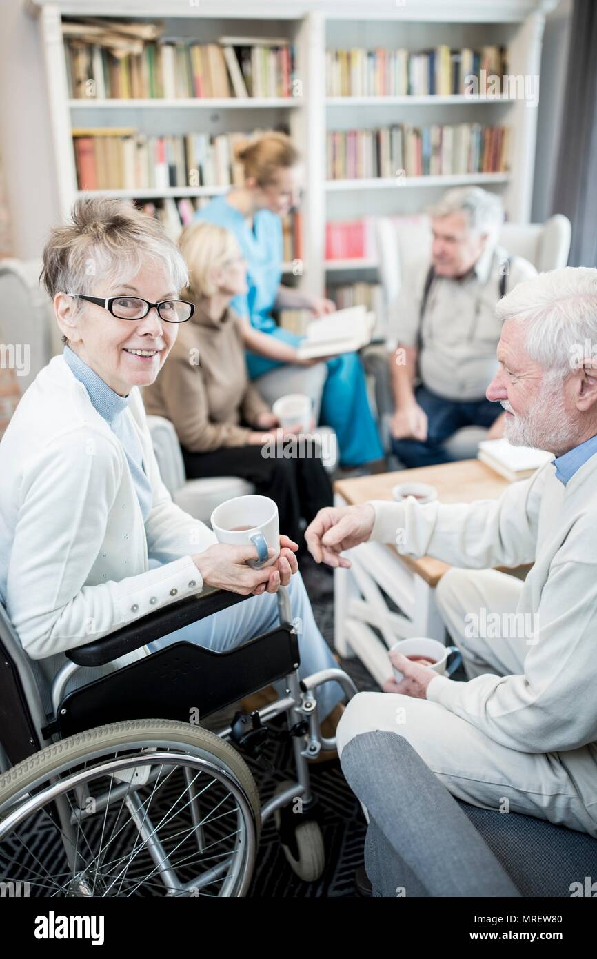Ältere Frau im Rollstuhl mit männlichen Unhold in Pflege zu Hause. Stockfoto