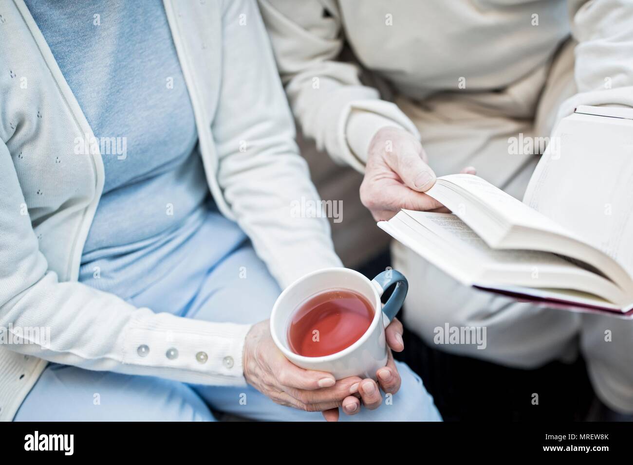 7/8-Ansicht von Frau mit teetasse und Mann mit Buch. Stockfoto
