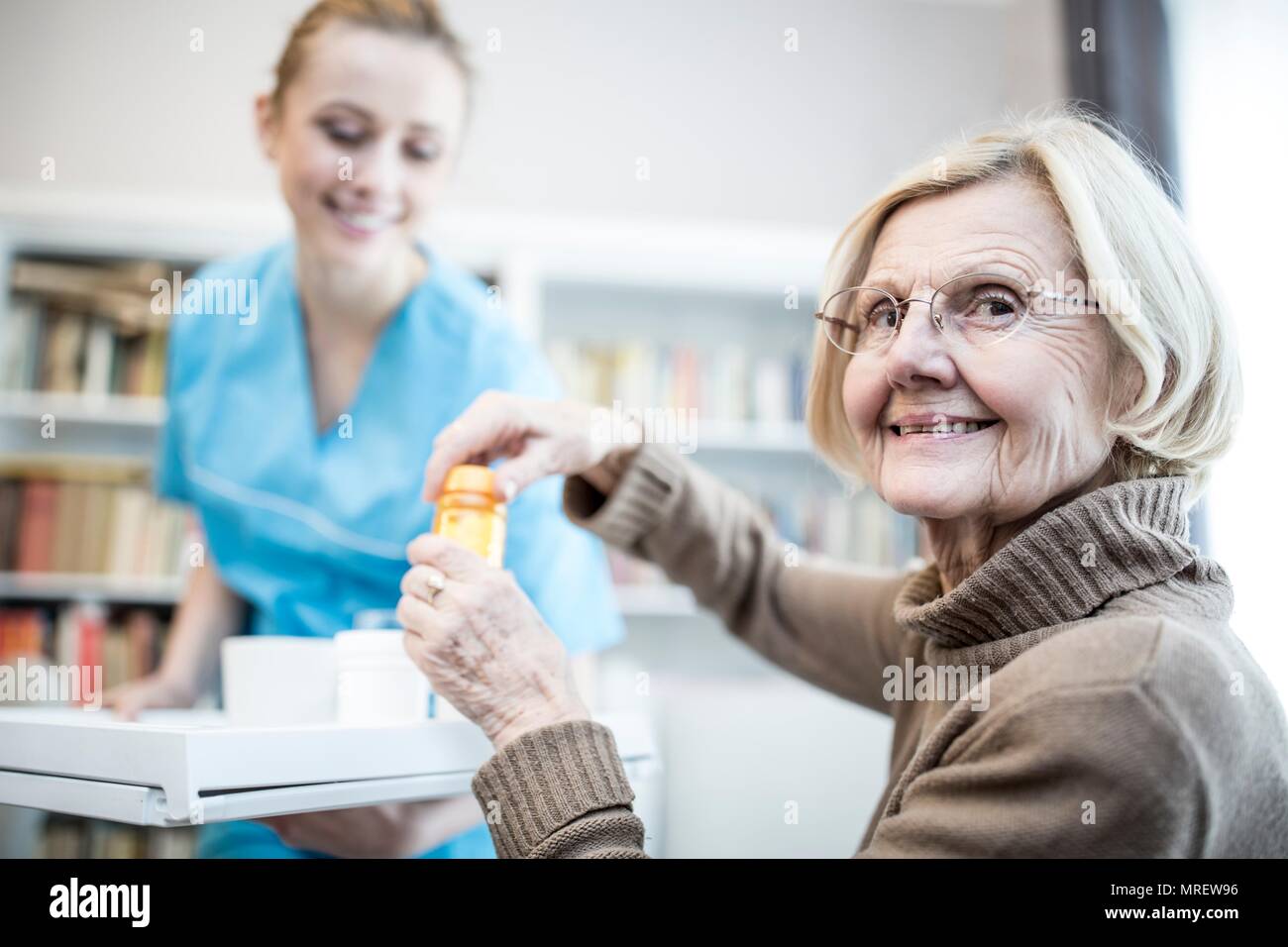 Ältere Frau Eröffnung Medizin Flasche und lächelnd. Stockfoto