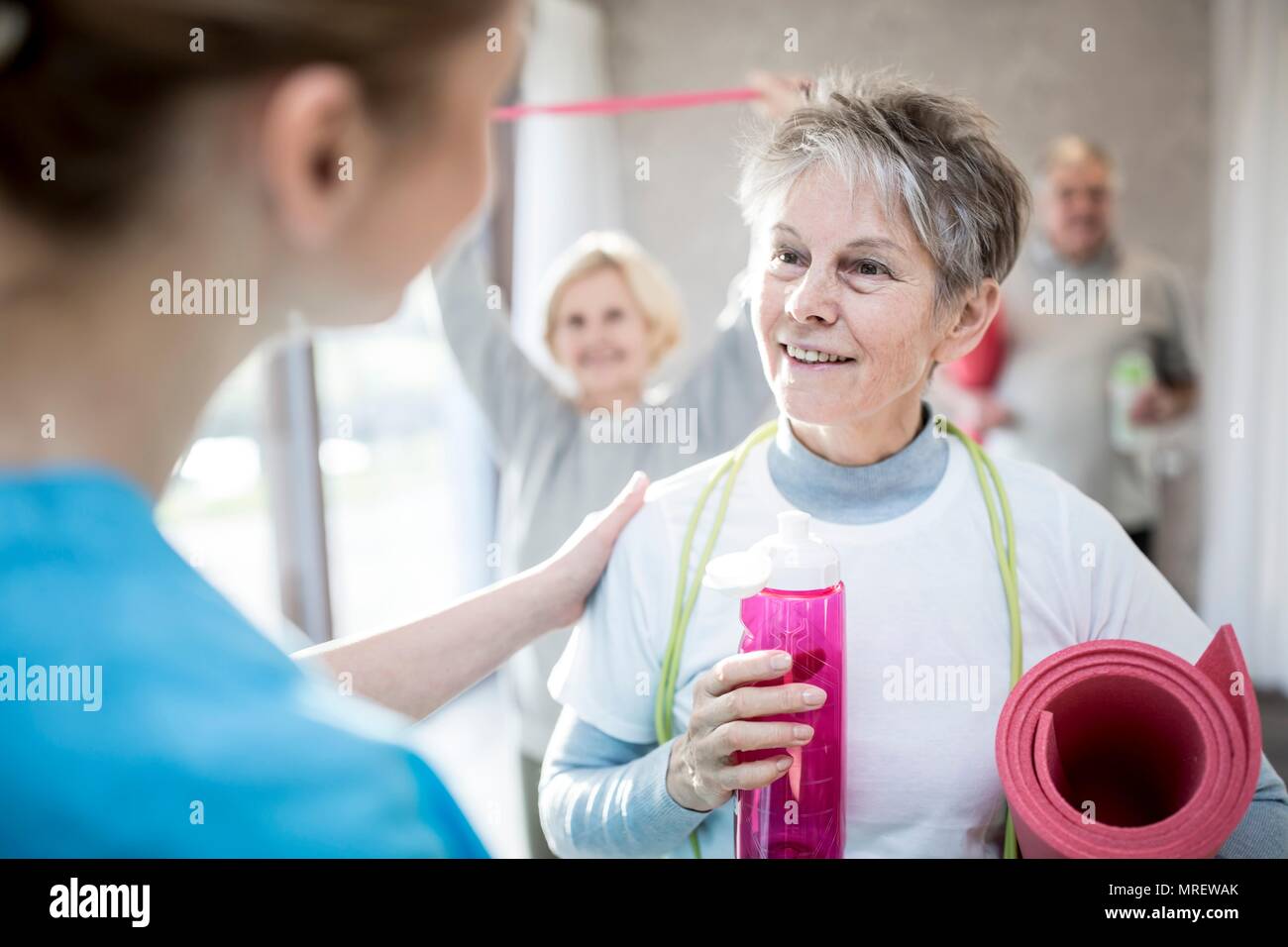 Ältere Frau im Gespräch mit Physiotherapeuten. Stockfoto